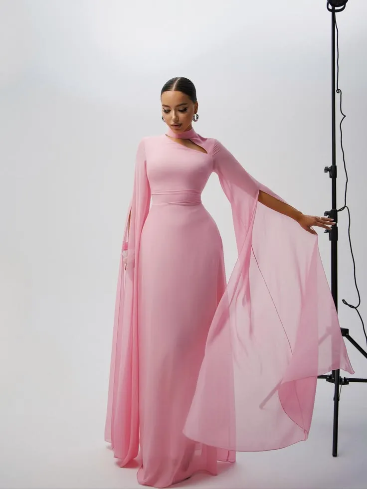 Woman in a powder pink gown with sheer cape sleeves