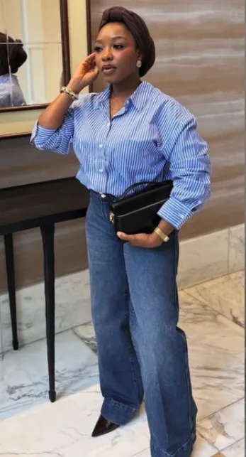 Woman in a blue button-up shirt tucked into wide-leg jeans